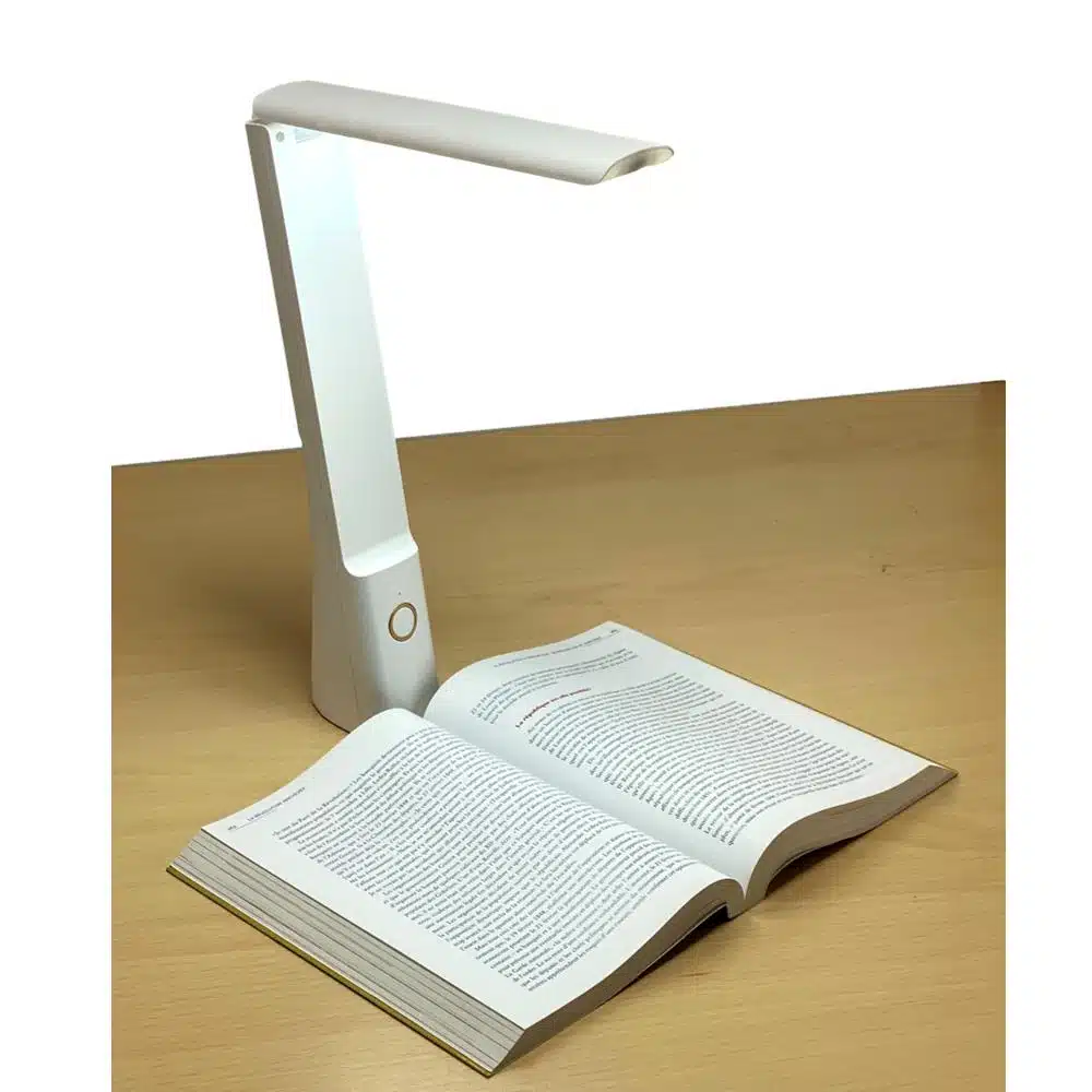 La lampe de basse vision EIRA posée sur un bureau, à coté d’un livre qu’elle éclaire